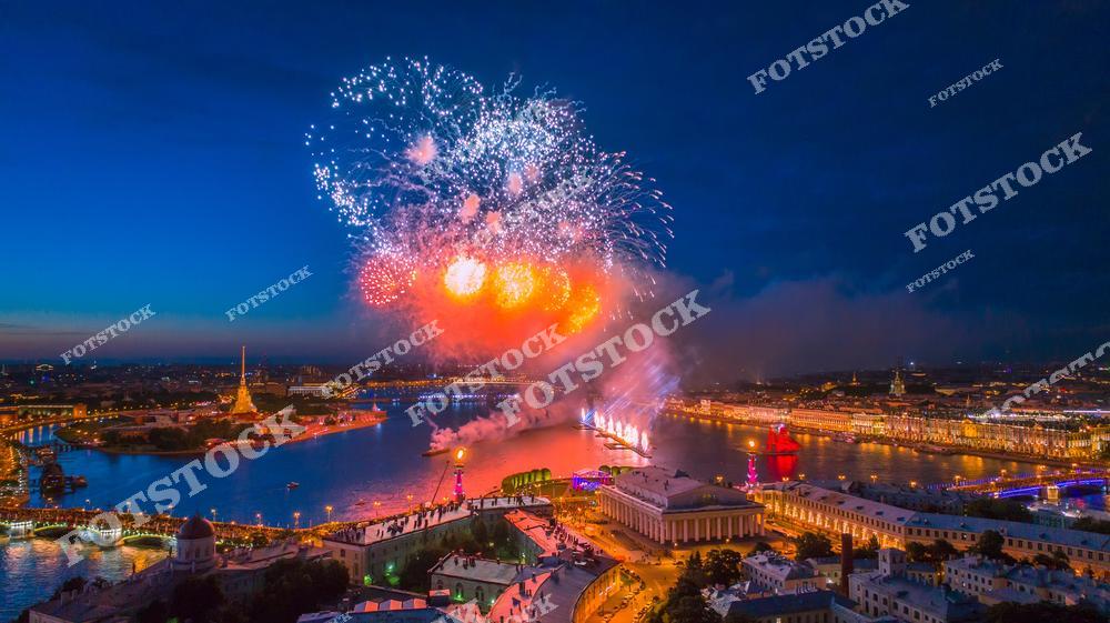 Панорамная фотография праздничного Санкт-Петербурга с высоты птичьего полета. На снимке видна река Нева, Петропавловская крепость и огни вечернего города, создающие атмосферу торжества. Съемка с дрона подчеркивает масштаб исторического центра, красоту архитектуры и городской панорамы. Фотография отражает праздничную атмосферу Петербурга, идеальна для публикаций о событиях в городе, туристических материалов, фотостоков, оформления интерьеров и рекламы. Вид с высоты позволяет увидеть городские улицы, мосты и уникальные панорамные виды Северной столицы России.
